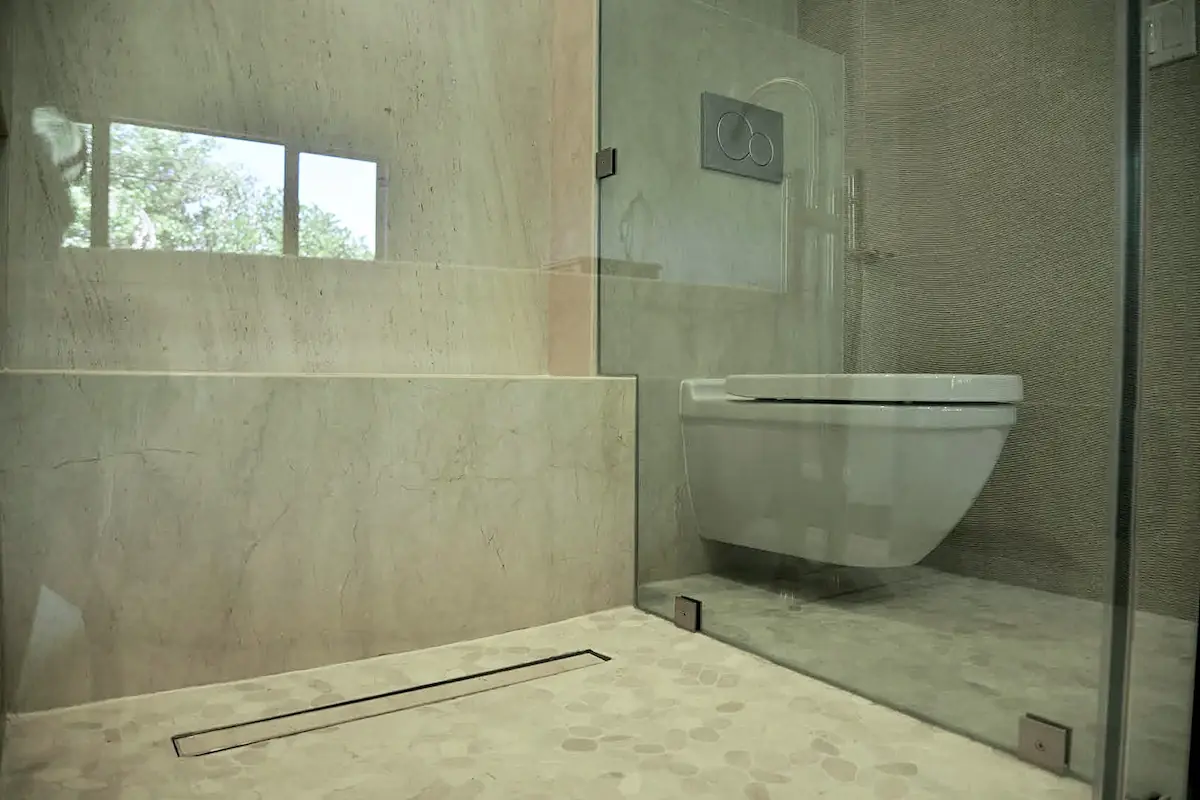 A bathroom with light stone floors and walls